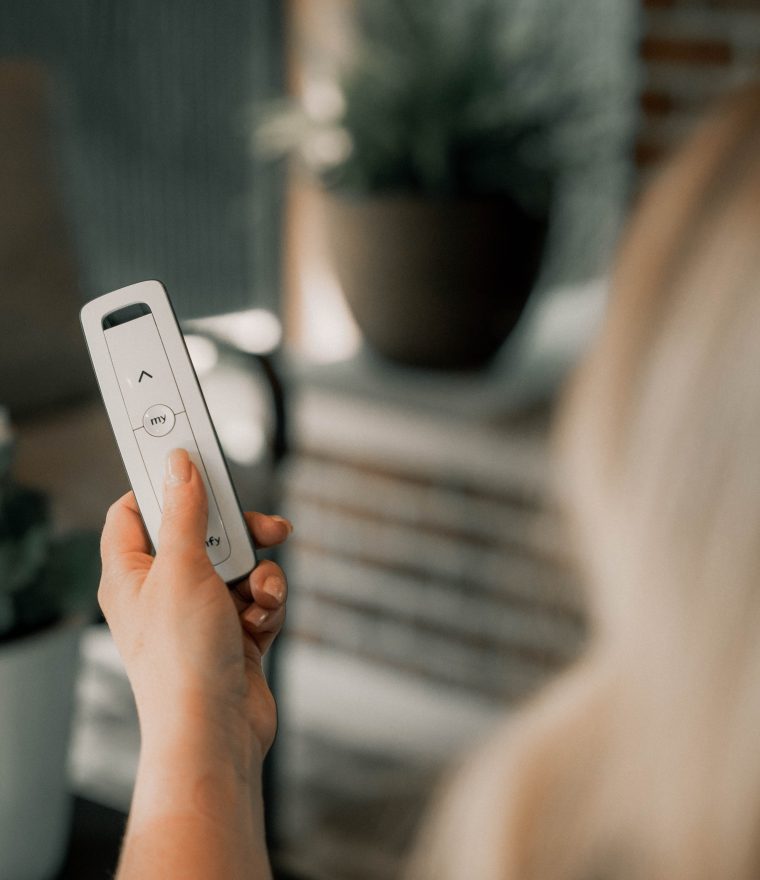 a person holding a Somfy&reg; motorized retractible screen controller in their hand